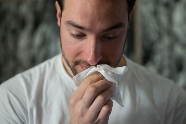 A person sneezing due to mold allergy